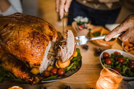 Close up of unrecognizable man carving roasted Thanksgiving turkey.