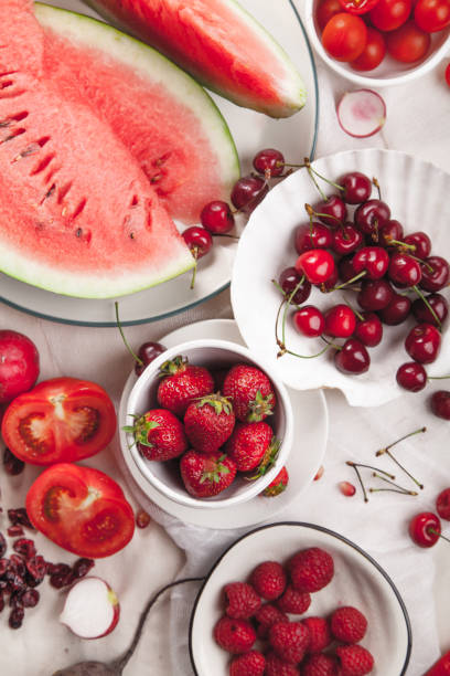 istock Red fruit and vegetable composition on linen fabric. Summer natural beauty concept with copy space. Vertical composition 984011458