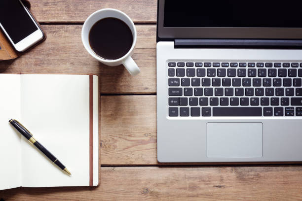 istock Open laptop with notepad and smartphone on desk from above 984011754