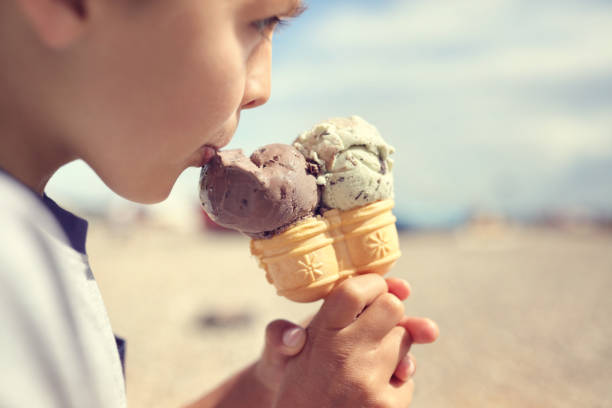 niño comer helado en la playa de vacaciones - ice cream licking little boys ice cream cone fotografías e imágenes de stock