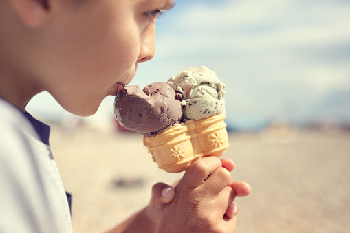Boy eating ice his cream cone on the beach on vacation