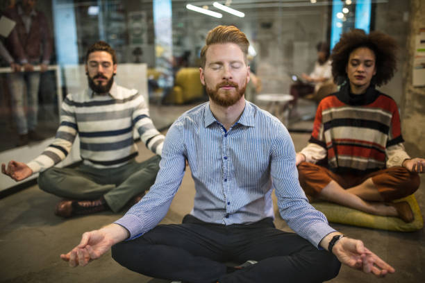 カジュアルなオフィスでヨガを行使リラックスしたビジネス人のチーム。 - zen like meditating yoga business ストックフォトと画像