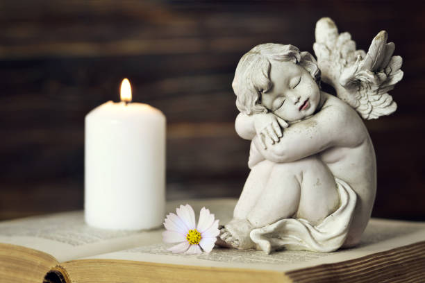 istock Angel, white candle and flower on the book 984029000