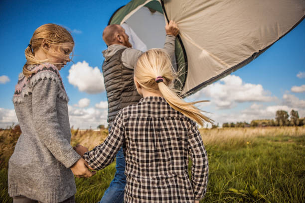 istock Handsome redhead father and blonde daughters chasing a tent caught in the wind on a camping holiday 984033088