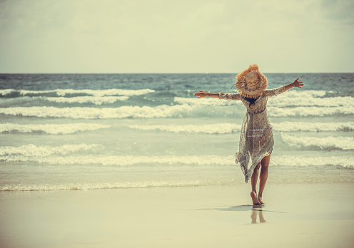 woman in a boho dress walking on the tropical beach