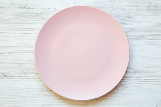 istock Empty pink plate on white wooden background. Top view, from above, flat lay. Dieting concept. 984033578