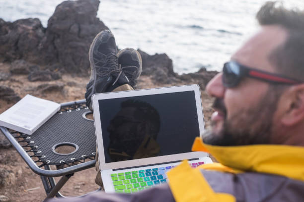 istock digital nomad at work in unusual office alternative open space on the coast sitting near the ocean waves. man in freedom activity far form cities and usual stressed lifestyle. 984036572