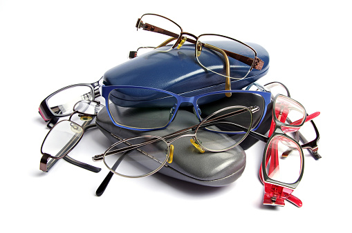 stack of old reading glasses and glass cases on a white background