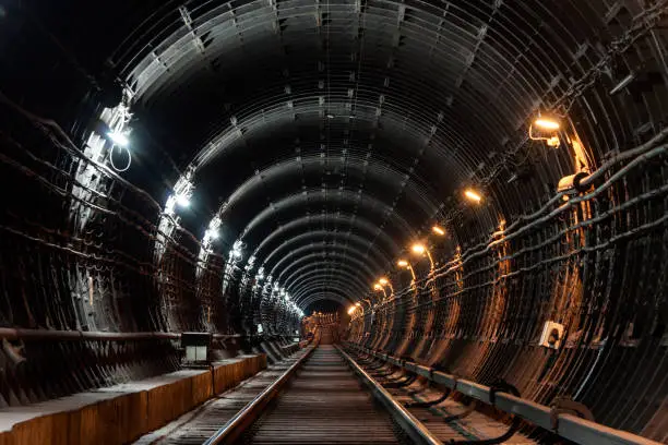 Straight circular subway tunnel with tubing and two different lights: white and yellow.