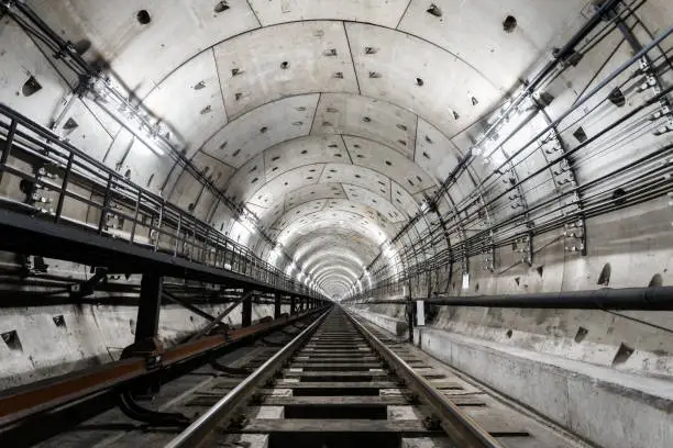 Photo of straight circular subway tunnel with a white lighting