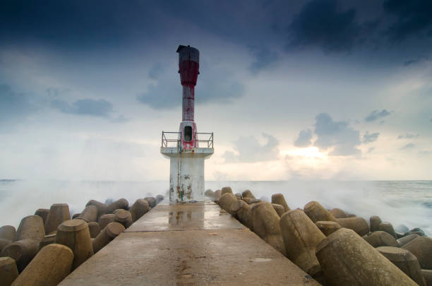 istock lighthouse and water break over beautiful sunrise scenery background 984054492
