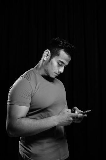 Studio portrait of male holding a cellphone over dark background