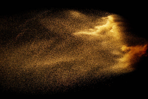 istock Abstract sand cloud. Golden colored sand splash agianst dark background. Yellow sand fly wave in the air. Sand explode on black background ,throwing freeze stop motion. 984102330