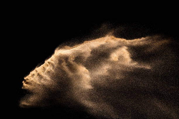 istock Abstract sand cloud. Golden colored sand splash agianst dark background. Yellow sand fly wave in the air. Sand explode on black background ,throwing freeze stop motion. 984102432