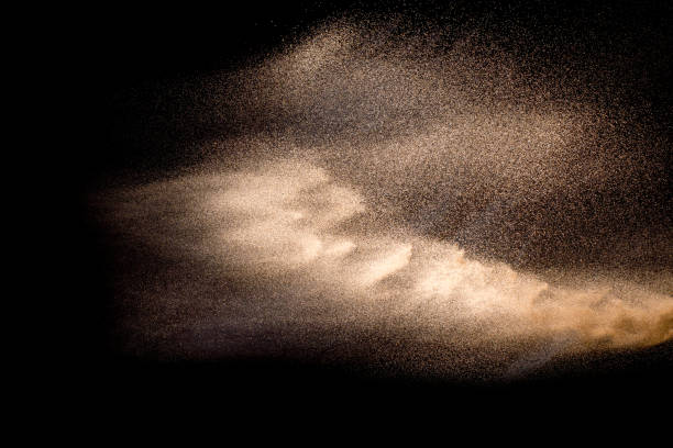 istock Abstract sand cloud. Golden colored sand splash agianst dark background. Yellow sand fly wave in the air. Sand explode on black background ,throwing freeze stop motion. 984102518