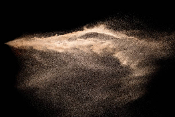 istock Abstract sand cloud. Golden colored sand splash agianst dark background. Yellow sand fly wave in the air. Sand explode on black background ,throwing freeze stop motion. 984102670