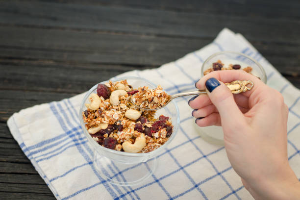 Female hand pours in yogurt granola. Traditional American Breakfast