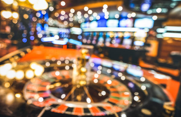 sfondo sfocato sfocato della roulette al salone del casinò - concetto di gioco d'azzardo con sala giochi sfocata con slot machine di video poker e luci sfocate multicolori - gioco dazzardo foto e immagini stock