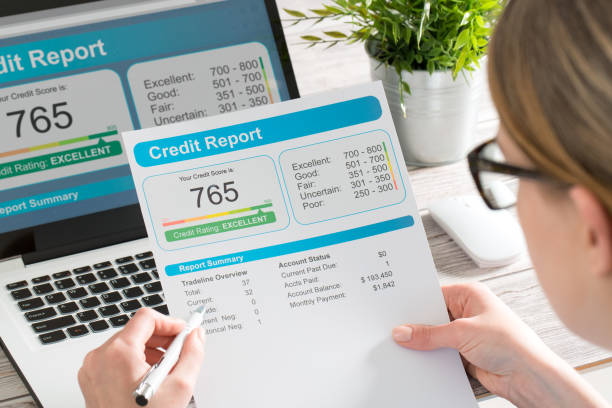 Credit score report on laptop and paper