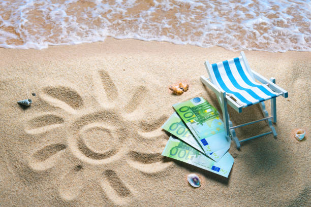 Deckchair with euro bills on a beach with a sun drawn on the sand stock photo