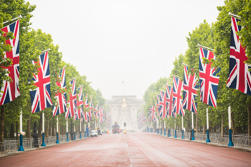 London, UK - September 14, 2022: A view of Buckingham Palace along the Mall lined with British flags on each side and police on duty to control the crowds.