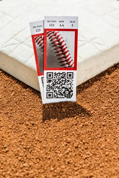 A low angle view of a pair of baseball game ticket stubs next to second base in the infield of a baseball diamond.