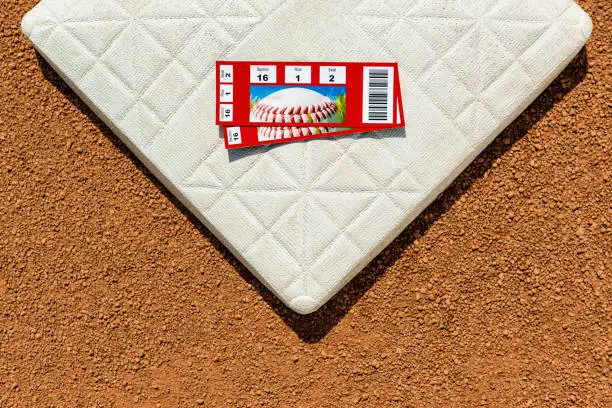 A high angle view of a pair of baseball game ticket stubs on second base in the infield of a baseball diamond.