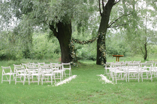 istock Tender flower arch for wedding and white chairs in park 984169772