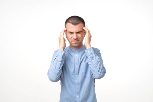 istock Portrait of young man having a headache while standing over white background. 984178764