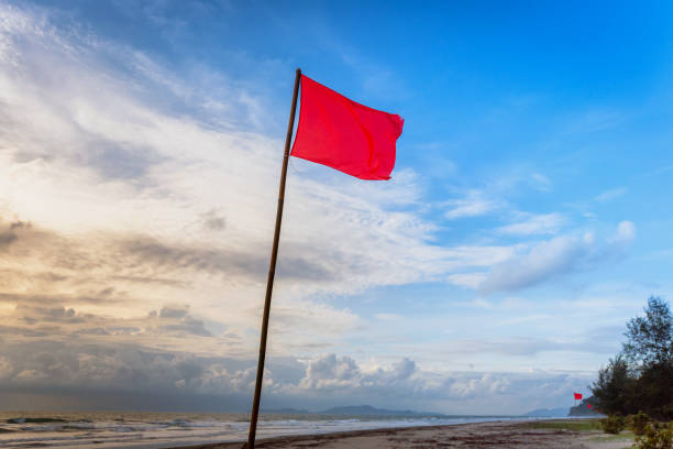 istock Red warning flag at beach.Swimming is dangerous in ocean waves. Red warning flag flapping in the wind on beach at stormy weather Phuket, Thailand. 984199220