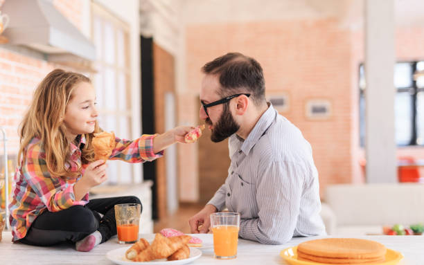 istock Little girl having fun on breakfast with father 984229752