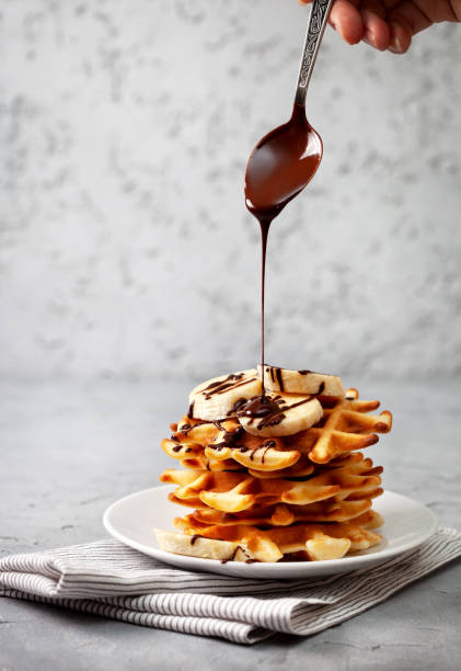 waffles with chocolate sauce belgian waffles with chocolate sauce and banana on a gray concrete background belgium photos stock pictures, royalty-free photos & images