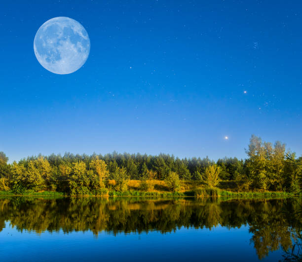 istock huge full moon above a quiet summer river at the dusk 984253654