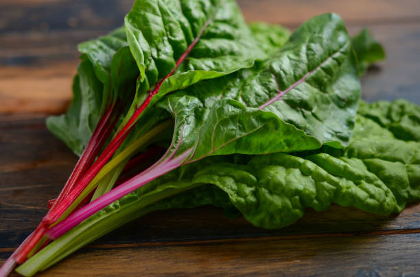 istock Fresh colorful chard leaves on old rustic wooden background. 984255418