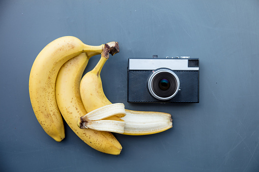 Vintage camera with banana on grey background. Above view
