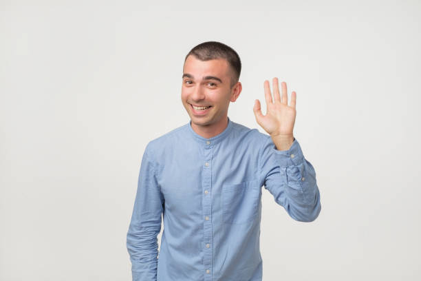 istock Man with blue shirt saying hello, waving a hand 984267764