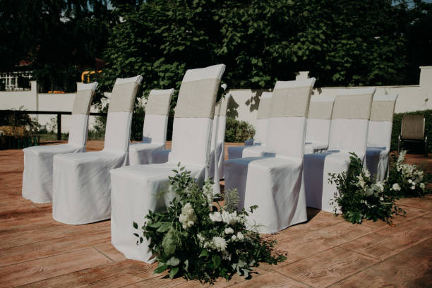 istock stylish chairs in white covers decorated with fresh flowers for wedding ceremony 984277194