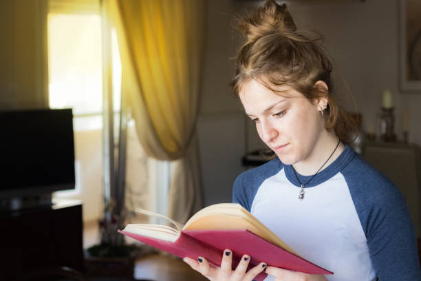 istock A young girl is reading a book standing at home. 984289938