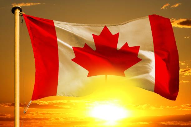 istock Canada flag weaving on the beautiful orange sunset with clouds background 984290610