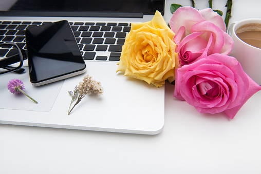 Desk with laptop, rose flowers,cup of coffe