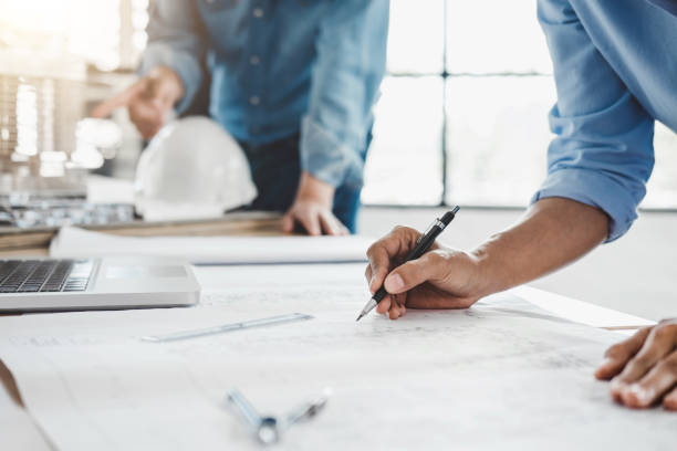 istock Hands of architect or engineer working on blueprint meeting for project working with partner on model building and engineering tools in working site, Construction concept 984291384
