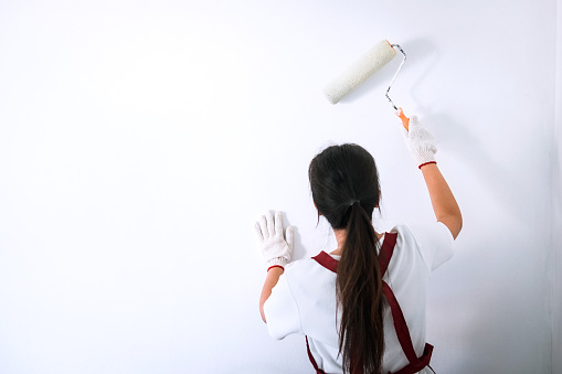 Interior working, Painter hand in white glove painting wall with paint roller in room, shape and structure.
