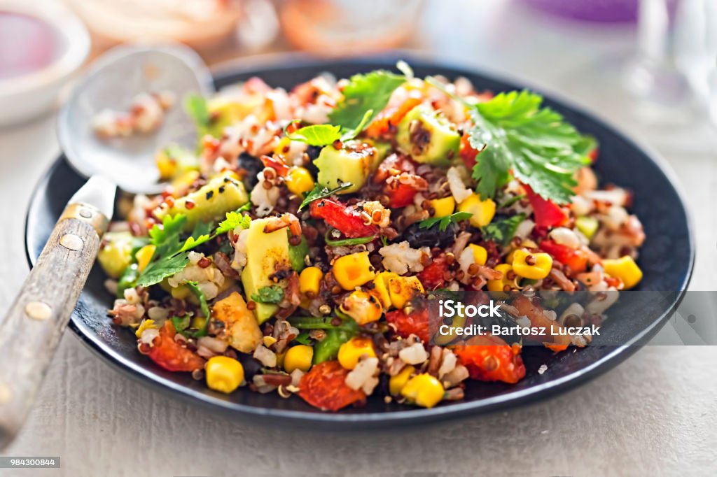 Negro frijoles, aguacate, maíz, tomate, arroz y quinua ensalada con aderezo de ají - Foto de stock de Ensalada libre de derechos