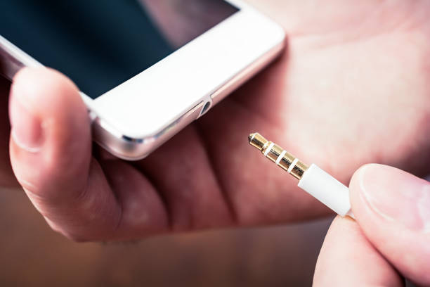 istock Headphone Jack Of A White Smartphone Gets Plugged In A White Headset Cable 984320710