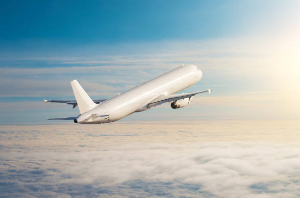 istock Flying airplane above the clouds horizon sky with bright sunset colors. 984342660