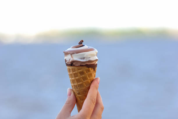 istock Ice cream cone, chocolate ice cream on blurred background, milk dessert on summer vacation, blank for designer with hand, copy space, milk product 984344112
