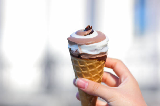 istock Ice cream cone, chocolate ice cream on blurred background, milk dessert on summer vacation, blank for designer with hand, copy space, milk product 984344242