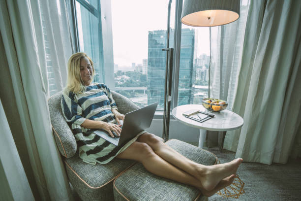 istock Young woman using computer in hotel room, business travel 984394660