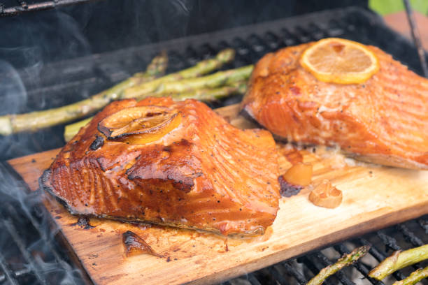 istock cedar plank salmon with lemon cooking on grill 984399490