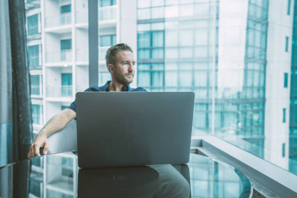 istock Young man using computer in hotel room, business travel 984415352